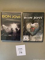 Two DVD cases of Bon Jovi DVDs placed side by side on a textured surface with a lot tag.