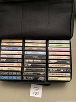 Photo of vintage rock music cassettes neatly arranged in a black zippered carrying case.