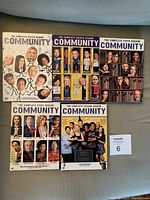 Five DVD box sets of Community TV series arranged in rows on a flat surface showing cover art and titles for seasons 1 through 5.