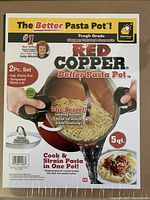 Close up photo of the packaging front showing the Better Pasta Pot branding, features like locking handles on lid, 5 quart capacity, and cooking/straining functionality.