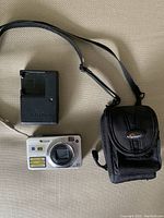 Sony DSC-W150 digital camera, battery charger, black carrying case with strap, and battery pack displayed