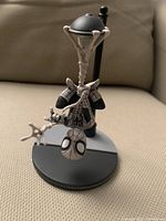 Front close-up photo showing Spider-Man figure hanging upside down with white webbing details and holding lamp post.