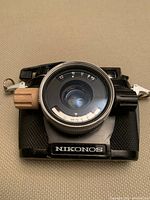 Front-facing view of black Nikonos camera body showing lens, aperture ring and shutter speed markings