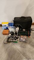 Full lot of electronics and accessories arranged on the floor showing all items together including cameras, headphones, radio, hard drive, flashlight and box