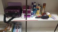 Shelf with two cosmetic bags, assorted lotions, moisturizers, hairspray, and hairbrushes.