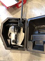 Top view of Craftsman Backwoods chainsaw inside black plastic carrying case, showing saw and part of case interior.