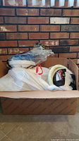 Box containing plastic bowls, utensils in bags, and other party goods.