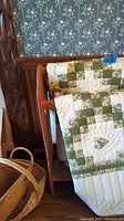 Photo showing the quilt draped over wooden quilt stand with basket in foreground