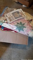 Folded colorful quilts and packaged valance curtains on top, visible patchwork and floral patterns.