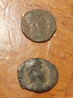 Two small ancient bronze coins shown on a flat surface, depicting worn profile busts of Constantine I.