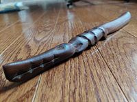 Close-up side angle showing carved crocodile head, textured scales, and the length of the wooden shoehorn laying on wooden floor.