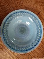 Top view of the round pottery bowl showing blue swirl pattern and textured edge inside bowl.