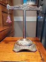 View of the plated silver earring stand with the two sets of custom shepherd hook earrings displayed, showing the overall decorative style and colors.