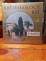 Front view of the sealed vintage archaeology kit box depicting Pompeii ruins and labeled as 'ARCHAEOLOGY KIT' and 'POMPEII'.