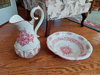 Photo showing entire bowl and jug set from the front on a wooden floor with floral armchair in background