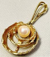 Front view of pendant showing textured spiral design with central cultured pearl.
