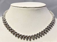 Front view of the silver necklace showing the beaded ball design along the chain and its reflective polished finish.