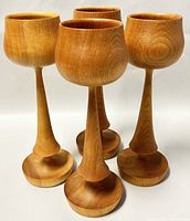 Front view of four teak wood goblets showing shape and finish.