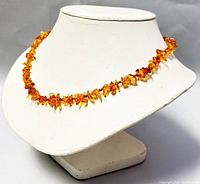 Full view of amber beaded necklace displayed on a white bust, showing details of beads and necklace length.