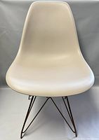 Front view of the white plastic modernist chair with geometric bronze metal wire base.