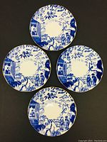 Four blue and white Royal Crown Derby Mikado pattern plates shown from top, arranged in pair over a dark surface.