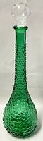 Full view of tall green bubble glass genie decanter with clear glass stopper sitting on top.