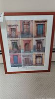 Full view of framed art print showing all nine doors, in a reddish wood frame resting against wall.