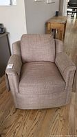 Front view of beige herringbone-pattern swivel rocker armchair
