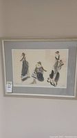Framed original art piece hanging on wall showing three abstract figures in watercolor and pencil