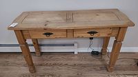 Front view of wooden sofa table showing two drawers with black metal handles and carved legs.