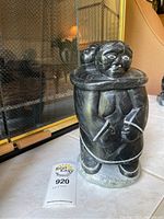 Front view of signed soapstone statue showing adult figure and child on back.