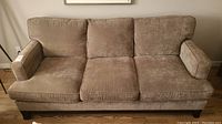 Front view of the three seater sofa upholstered in a soft brown/taupe fabric with removable cushions and square arms