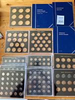 10 plastic coin holders for various Canadian coin denominations along with three blue coin holder booklets arranged on a surface.