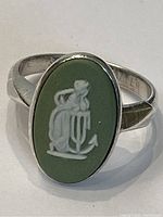 Close-up image of the sterling silver ring with an oval green Jasperware stone featuring a white classical figure in relief.