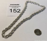 Image showing the full length of thick twisted sterling silver rope chain necklace next to a quarter for size reference.