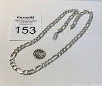 Full view of the sterling silver necklace laid flat next to a quarter for size reference.