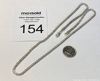 Full view of sterling silver rope chain necklace with a Canadian dime for size reference.