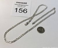Full view of silver necklace chain beside Canadian quarter for scale.