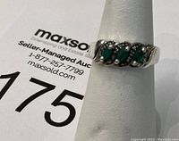 Ring shown on a white ring holder against a white background with auction lot card.
