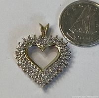 Heart-shaped 10K gold diamond pendant next to Canadian 10¢ coin for scale