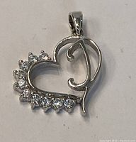 Front and angled view of the sterling silver heart-shaped pendant with white stones and the letter "D" integrated into the design.