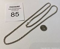 Full length view of the sterling silver rope chain necklace laid out with a Canadian quarter for size reference and auction lot card.