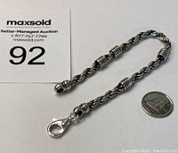 Full view of sterling silver bracelet with lobster clasp and Canadian quarter for scale.