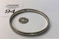 Twisted rope design sterling silver bangle with a US quarter coin for size reference.