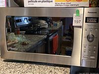 Front view of the Panasonic microwave oven showing the reflective door and control panel with dial and buttons.