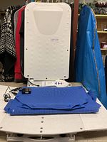Full view of white plastic unit with blue fabric seat cover folded in front on table