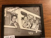 Full photo showing the framed black and white image of The Honeymooners cast in bus window.
