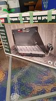 Box showing image and branding of Coleman Propane Stove with two burners, taped shut.
