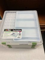 Stack of four clear ArtBin Super Satchel Series storage containers with green locking tabs, showing front and side views