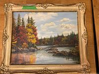 Full view of original landscape painting in ornate gold frame showing river, rocks, and autumn trees.